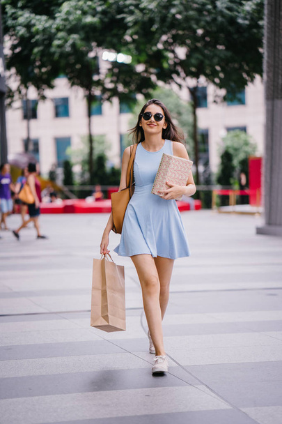 young, fashionable and happy young Indian Asian woman in a blue dress walking down a street in the shopping district  - Φωτογραφία, εικόνα