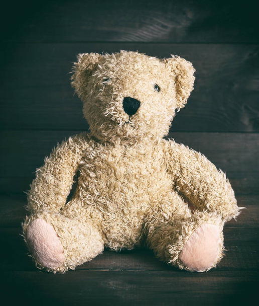 brown soft teddy bear sit on a brown wooden background, vintage toning - 写真・画像