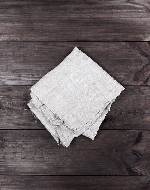 gefaltetes graues Handtuch auf braunem Holzhintergrund, Draufsicht - Foto, Bild