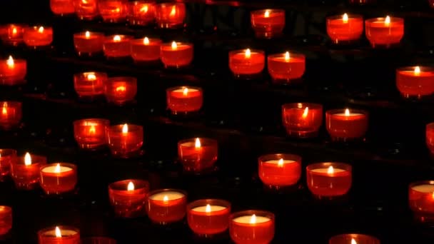 Ř. křesťanská modlitba červené kulaté votivní svíčky hořet ve tmě. Modlitba, osvětlení obětní svíčky. Hořící svíčky památník v katolické církvi. Slaví Vánoce v katedrále - Záběry, video