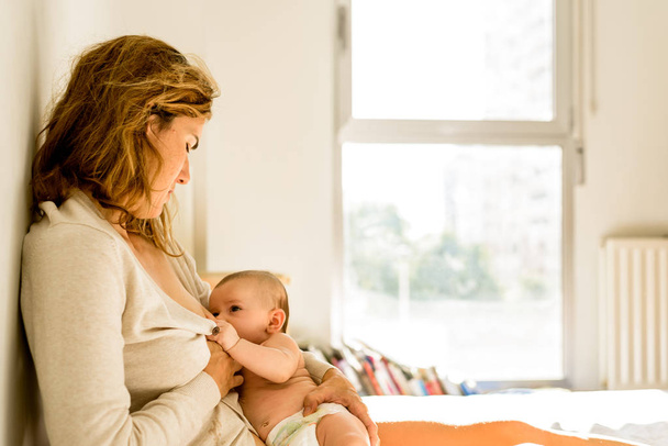 Baby borstvoeding door zijn moeder in bed rustig in de ochtend, gezonde moederschap concept. - Foto, afbeelding