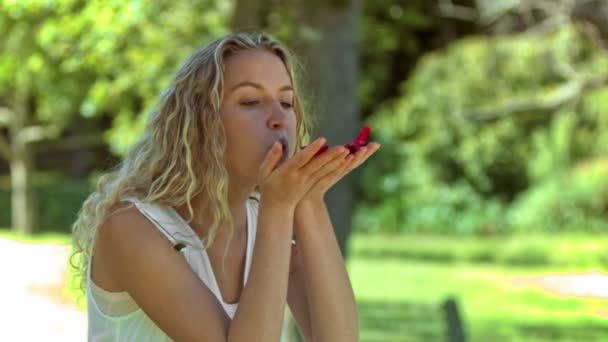 Blonde woman blowing in slow motion on petals - 映像、動画
