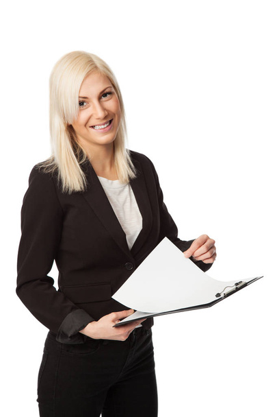 An attractive businesswoman wearing a black suit and white shirt, holding a clipboard, standing against a white background. - Foto, Bild