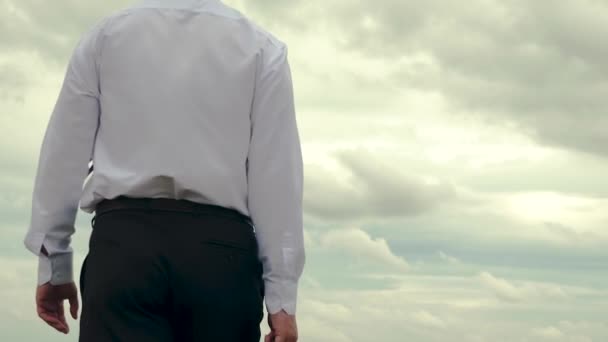 Ernstige man in wit overhemd met werkmap in zijn hand gaat aan het werk tegen de achtergrond van de sombere donkere hemel. Terug vie - Video