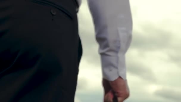 Hand close-up. Serious man in white shirt with briefcase in his hand goes to work against background of gloomy dark sky. Back view. - Footage, Video