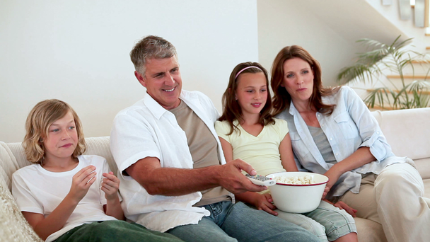 Family eating popcorn while watching the television - Filmagem, Vídeo