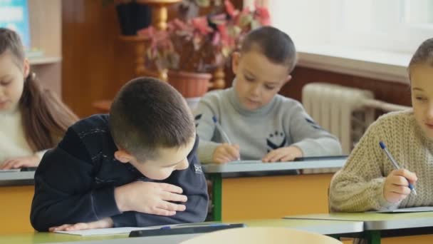 Les enfants écrivent assis à un bureau
 - Séquence, vidéo