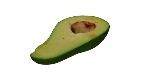 Realistische weergave van een draaiende groene Florida avocado (doormidden gesneden) op witte achtergrond. De video is naadloos looping, en het object is 3d gescand van een echte avocado. - Video