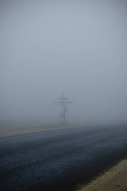 Cruz de metal na estrada no nevoeiro
 - Foto, Imagem