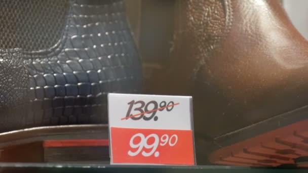 Botas de lujo de cuero costosas en la tienda de escaparate de zapatos junto a la etiqueta de precio de descuento de cerca ver
 - Imágenes, Vídeo