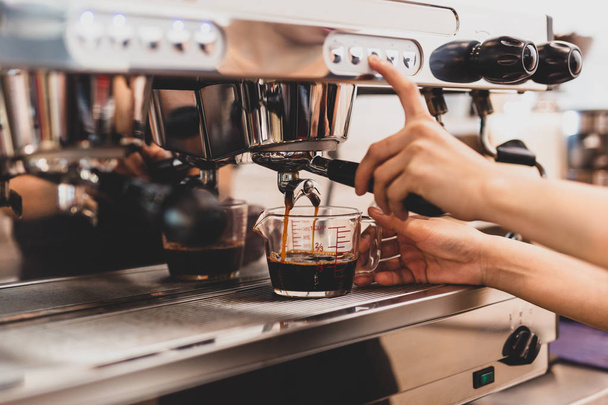 Mains de barista femelle appuyant sur le bouton sur la machine tout en faisant du café frais
 - Photo, image