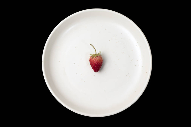 Strawberry in a white plate on a black background. - Zdjęcie, obraz
