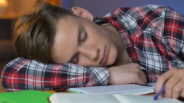 Tired schoolboy sleeping on table, preparation for exam, overworked student - Кадры, видео