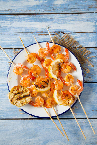 grilled shrimp skewers on wooden surface - 写真・画像
