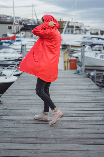 Beautiful young woman in a red cloak in the yacht port. Stockholm, Sweden - Фото, изображение
