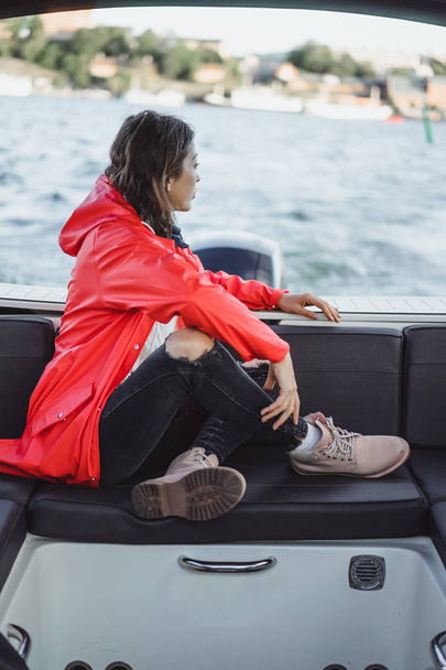 beautiful young woman in a red raincoat rides a private yacht. Stockholm, Sweden - Foto, Imagen