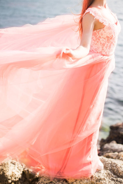 High beautiful bride in a long coral wedding dress on the sea, from behind. The concept of fashion colors 2019 - Valokuva, kuva