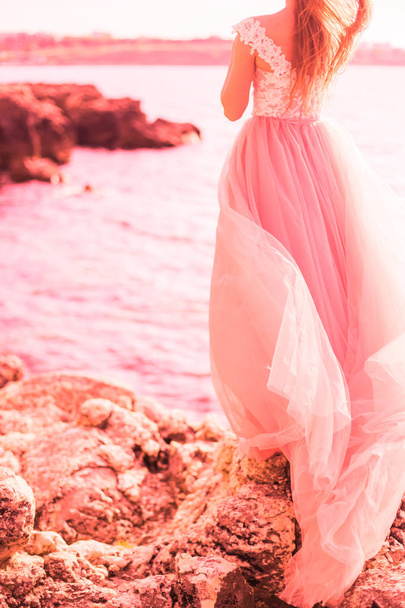 Beautiful bride in a long pink wedding dress on the sea. The concept of fashion colors 2019, living coral - Photo, Image