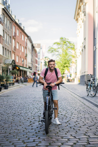 young man riding bicycle on the street - Фото, изображение