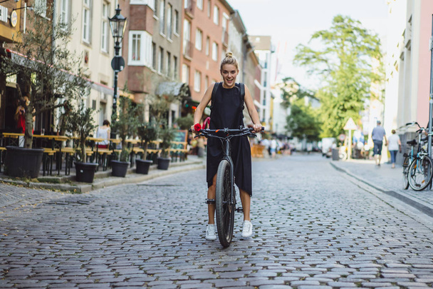 都会で自転車に乗っている若い女性は - 写真・画像