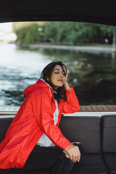 beautiful young woman in a red raincoat rides a private yacht. Stockholm, Sweden - Фото, зображення