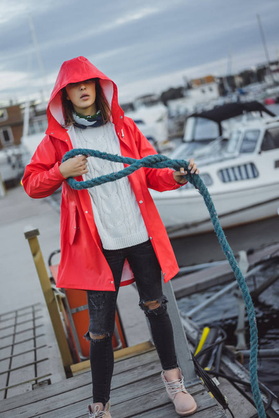 Beautiful young woman in a red cloak in the yacht port. Stockholm, Sweden - 写真・画像