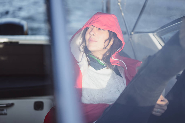 beautiful young woman in a red raincoat rides a private yacht. Stockholm, Sweden - Фото, изображение