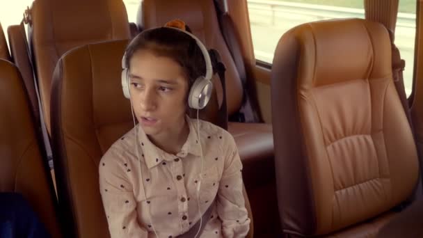 das Konzept der Sommerferien, Reisen. Teenie-Mädchen fährt im Minivan mit Kopfhörern - Filmmaterial, Video