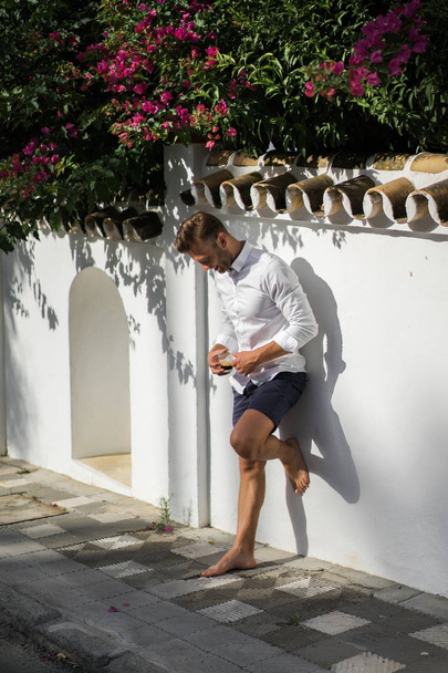 man in white shirt drinks coffee outdoors in summer - Zdjęcie, obraz