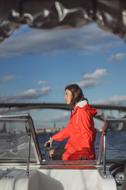 beautiful young woman in a red raincoat rides a private yacht. Stockholm, Sweden - Fotoğraf, Görsel