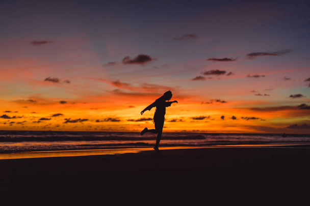 people on the beach at sunset. the girl is jumping against the backdrop of the setting sun. - Fotó, kép