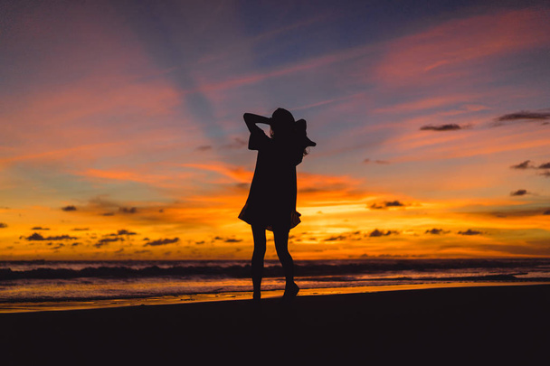 people on the beach at sunset. the girl is jumping against the backdrop of the setting sun. - Foto, imagen