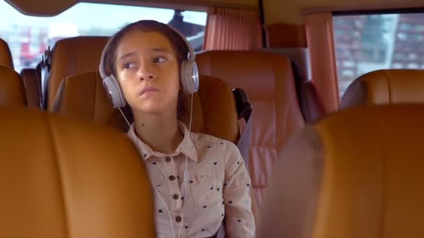 The concept of summer vacation, travel. teen girl rides in a minivan with headphones - Video
