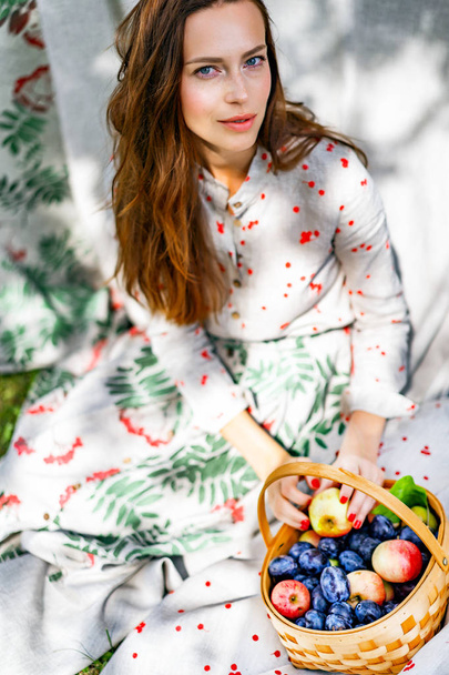 young woman with a basket of fruits, plums and apples. - Foto, Imagem