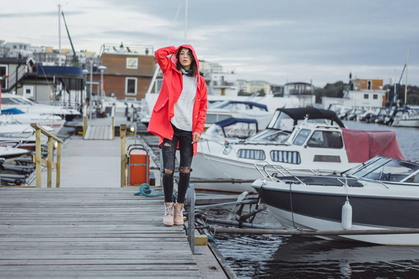 Beautiful young woman in a red cloak in the yacht port. Stockholm, Sweden - Фото, изображение