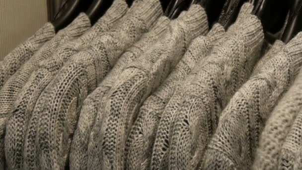 Modieuze collectie warme kleren. Groot aantal nieuwe warme stijlvolle truien van verschillende kleuren opknoping op hangers in de kleding bewaren shopping center of mall. - Video