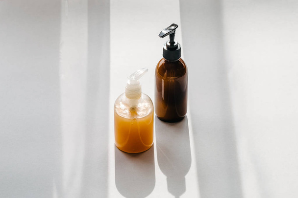 Botellas transparentes de plástico y vidrio marrón con cosméticos orgánicos de arriba. Luz directa. Concepto de minimalismo de blogs de belleza
 - Foto, imagen