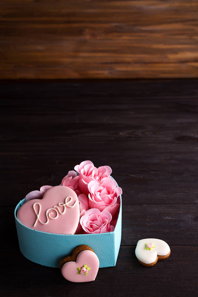 Bolachas de corações na caixa. Caixa azul redonda festiva com biscoitos e rosa em fundo de madeira escura, espaço de cópia
 - Foto, Imagem