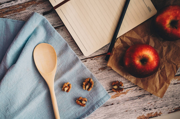 Cooking a recipe book with apple walnuts and spoon on wooden and blue background - Fotografie, Obrázek