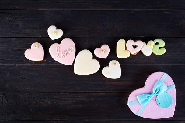 Süßigkeiten am Valentinstag. Kekse in Herzform und mit Schriftzug Liebe auf dunklem Holzhintergrund - Foto, Bild