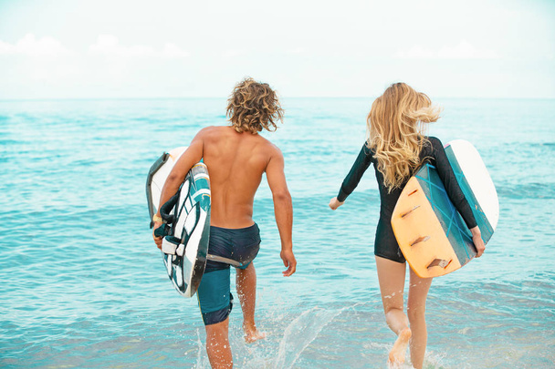 Surffaajat rannalla Hymyilevät surffaajat kävelevät rannalla ja pitävät hauskaa kesällä. Extreme urheilu ja loma käsite
 - Valokuva, kuva