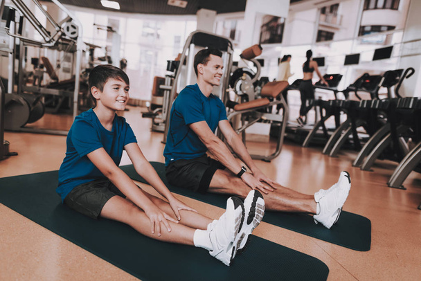 Young Father and Son Doing Exercises in Sport Club. Healthy Lifestyle Concept. Sport and Training Concepts. Modern Sport Club. Sport Equipment. Family Sport. Running Tracks. Parent with Child. - Zdjęcie, obraz