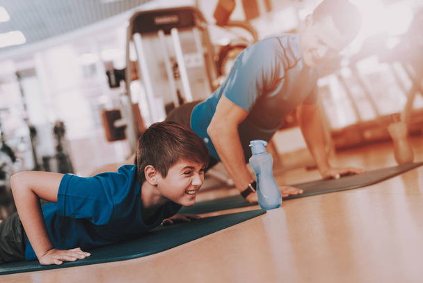 Young Father and Son Doing Exercises in Sport Club. Healthy Lifestyle Concept. Sport and Training Concepts. Modern Sport Club. Sport Equipment. Family Sport. Running Tracks. Parent with Child. - Фото, изображение