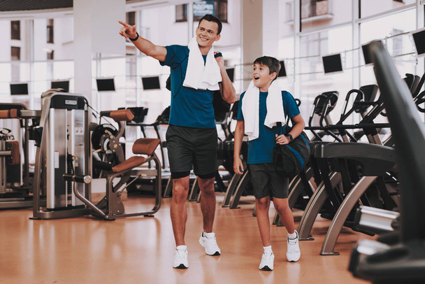 Young Father and Son near Treadmills in Modern Gym. Healthy Lifestyle Concept. Sport and Training Concepts. Modern Sport Club. Sport Equipment. Family Sport. Running Tracks. Parent with Child. - 写真・画像