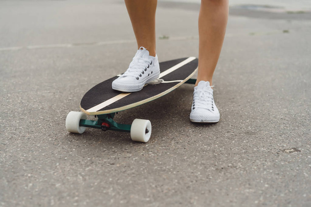 girl with long hair skates on a skateboard. street, active sports - Φωτογραφία, εικόνα