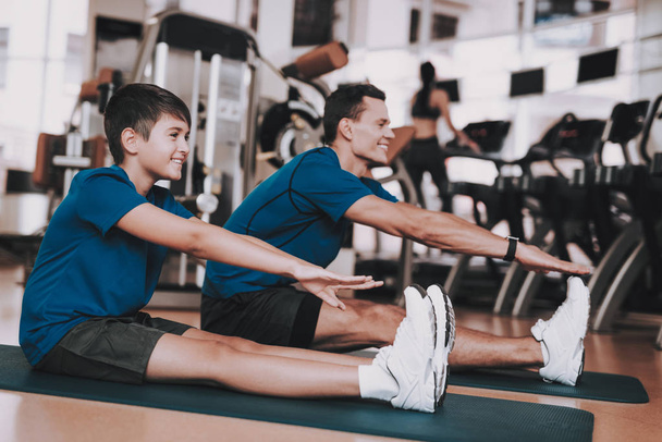 Young Father and Son Doing Exercises in Sport Club. Healthy Lifestyle Concept. Sport and Training Concepts. Modern Sport Club. Sport Equipment. Family Sport. Running Tracks. Parent with Child. - Foto, imagen