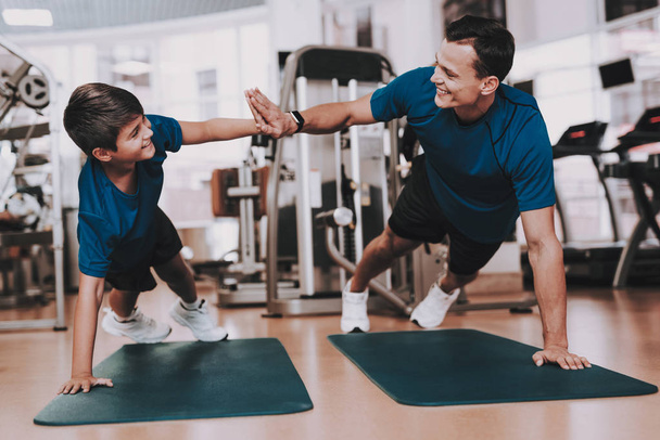 Young Father and Son Doing Exercises in Sport Club. Healthy Lifestyle Concept. Sport and Training Concepts. Modern Sport Club. Sport Equipment. Family Sport. Running Tracks. Parent with Child. - Photo, Image