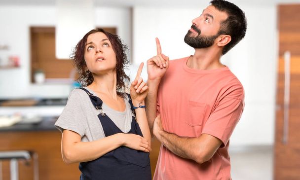 Пара з вагітною жінкою, вказуючи пальцем чудова ідея і дивлячись вгору всередину будинку
 - Фото, зображення