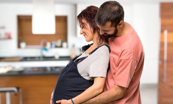 Pariskunta raskaana oleva nainen halaus talon sisällä
 - Valokuva, kuva