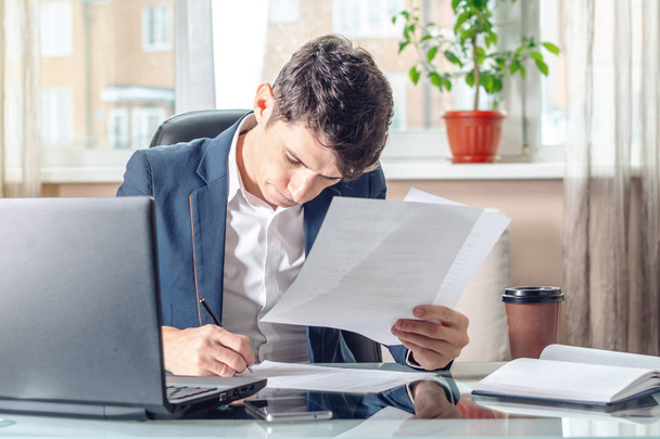 Man businessman sitting at the table signing documents in the office. Concept of registration of transactions and work with securities - Fotó, kép